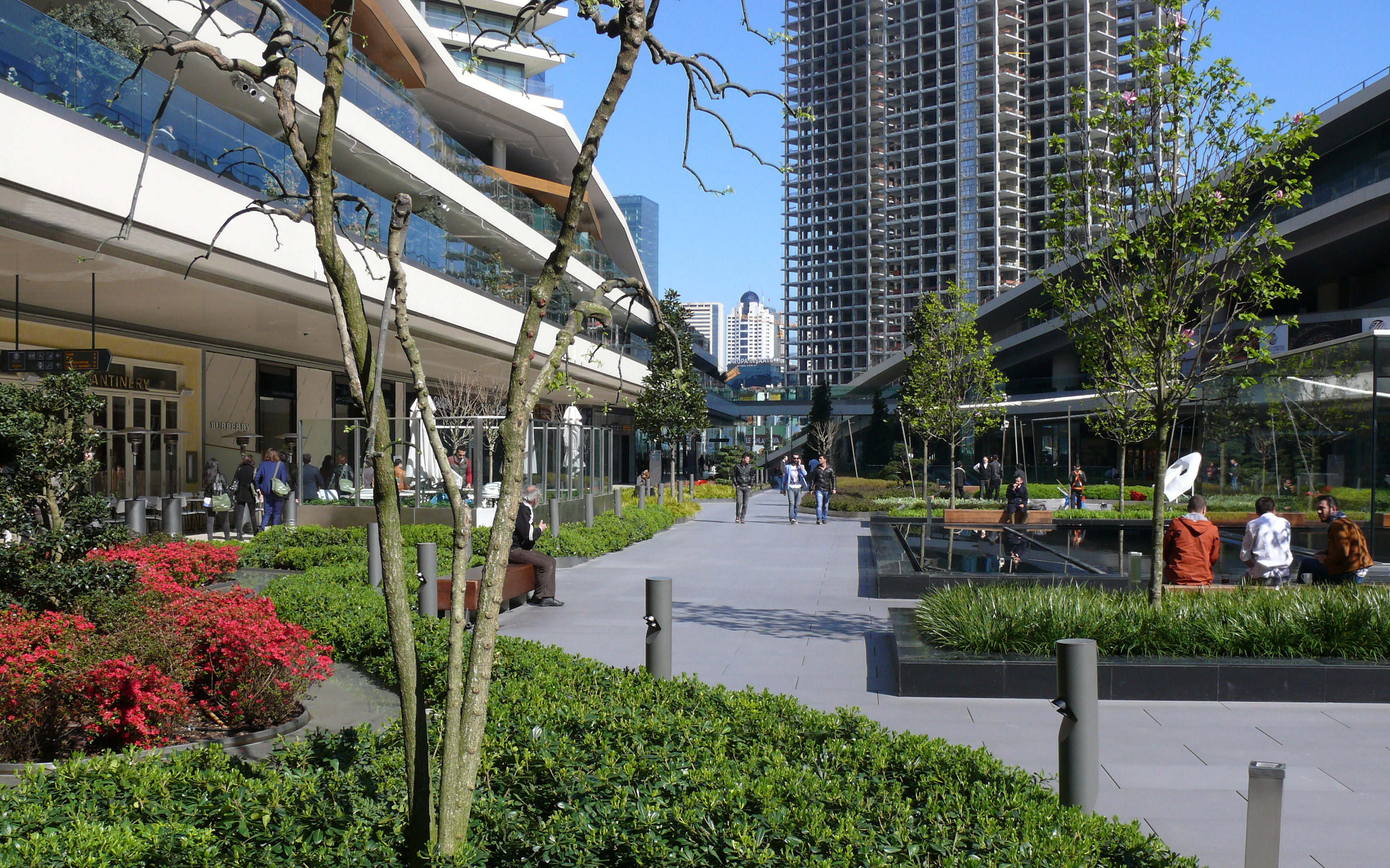 La gente en un centro comercial con áreas verdes para sentarse