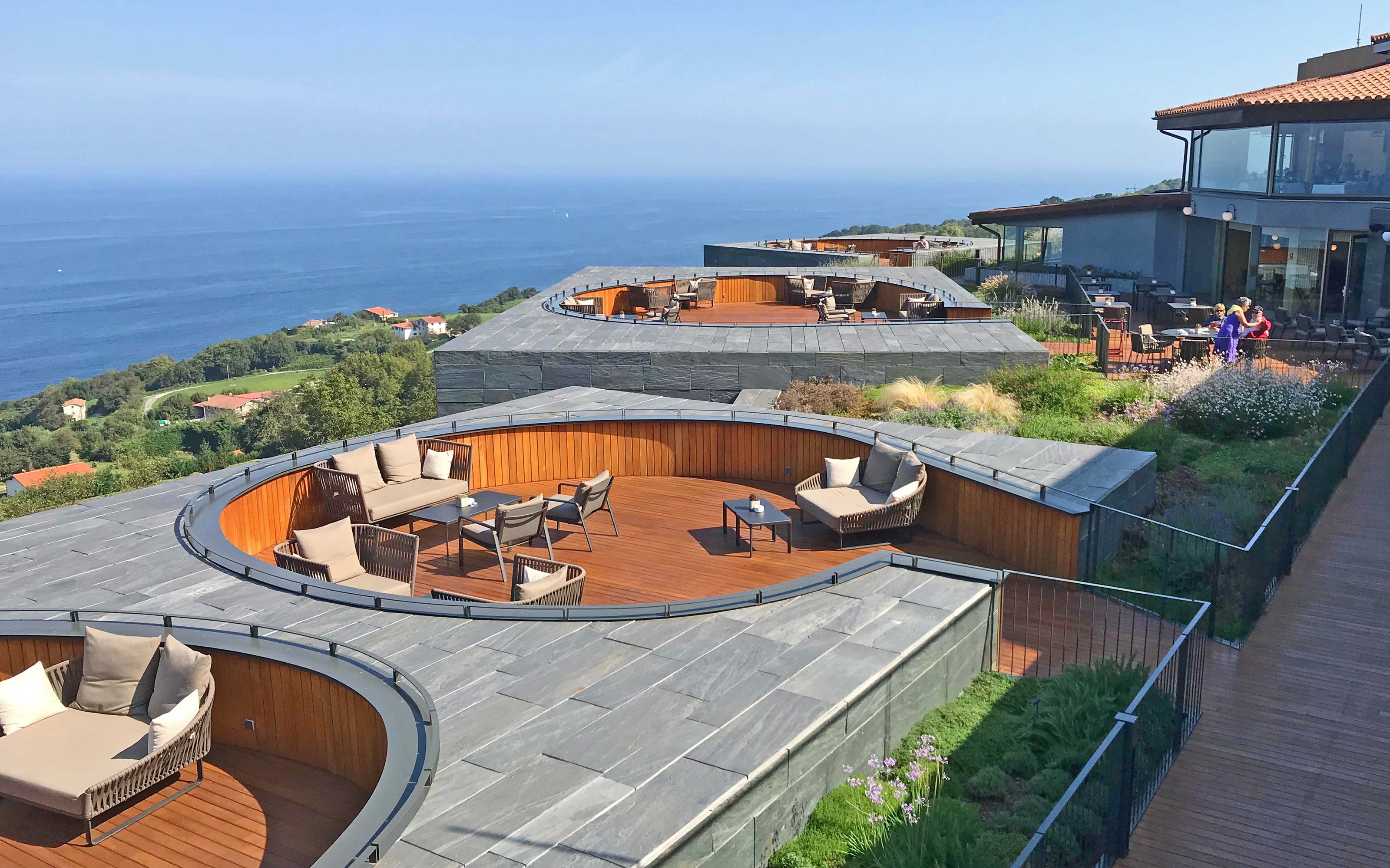 Cubierta jardín con zona de asientos de madera y vista al mar