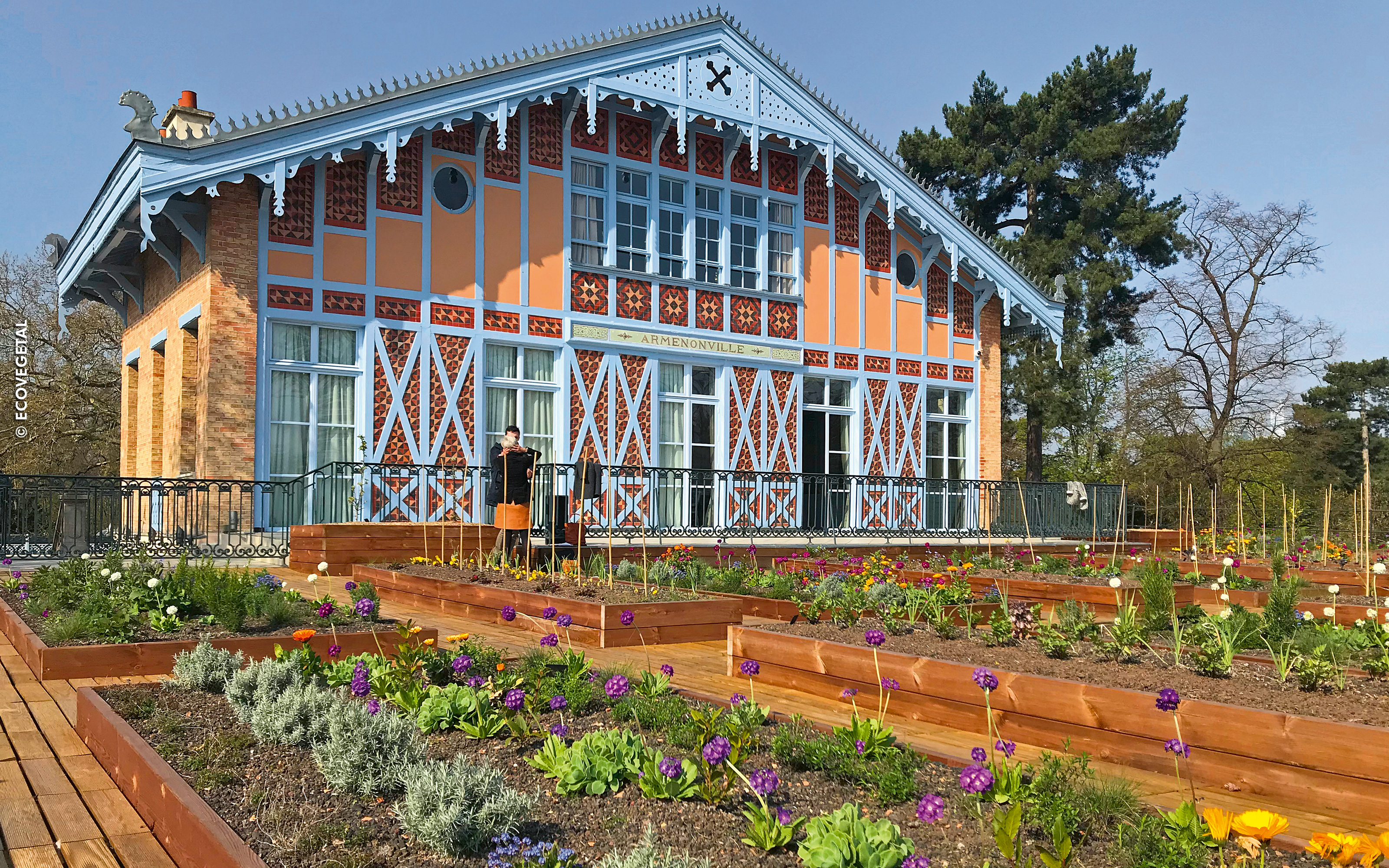 Gente y huertos enfrente de un edificio histórico 